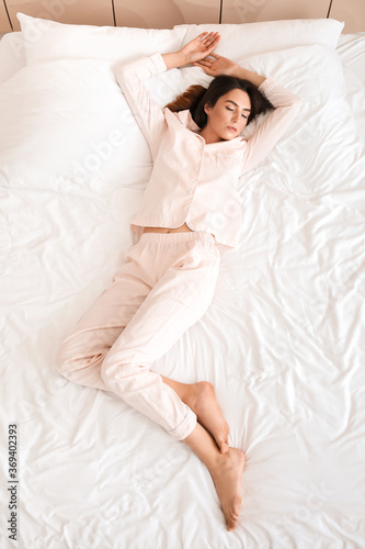 Young woman sleeping in bed, top view