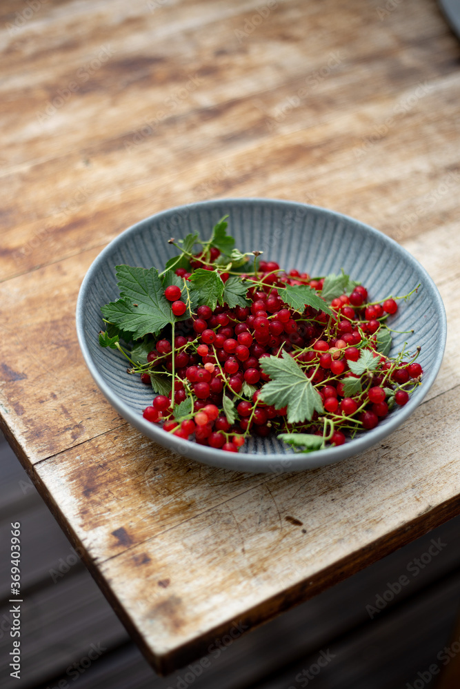 Red currant in a rustic plate on a old brown wooden background Red currant in a rustic plate on a old brown wooden background