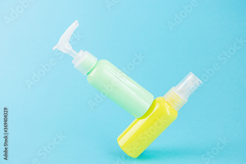 Yellow and blue cosmetic bottles on the same colored background. Stylish concept of organic essences, beauty and health products. Copy space, minimalism, levitation effect.