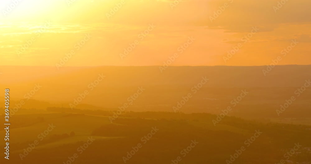 Orange sunset close-up view of a landscape with hills and houses lying in a valley with moving to the side. Orange sunset close-up view of a landscape with hills and houses lying in a valley with moving to the side.