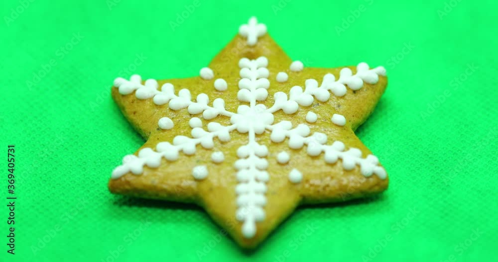 Zoomed in a gingerbread pastry with white decorations on top in the shape of a Christmas star on a green background. Zoomed in a gingerbread pastry with white decorations on top in the shape of a Christmas star on a green background.
