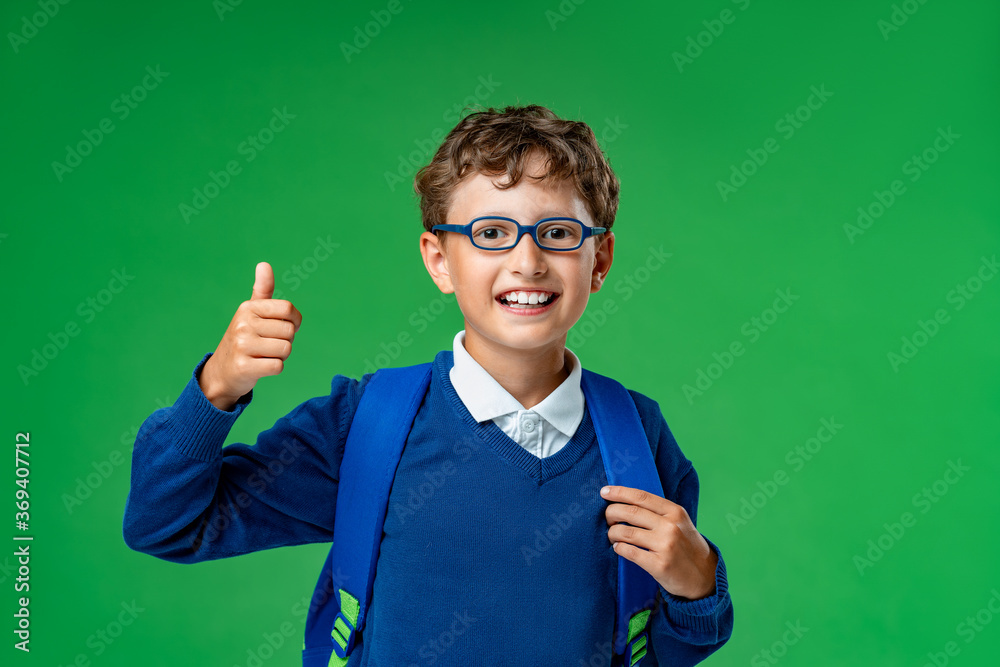 Smiling schoolboy in glasses, uniform with a backpack, shows the class in the Studio