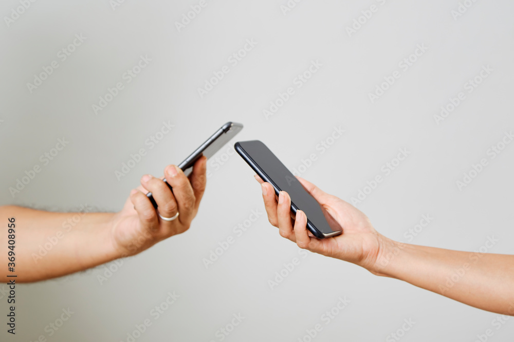 A male and female hands with phones opposite each other A male and female hands with phones opposite each other
