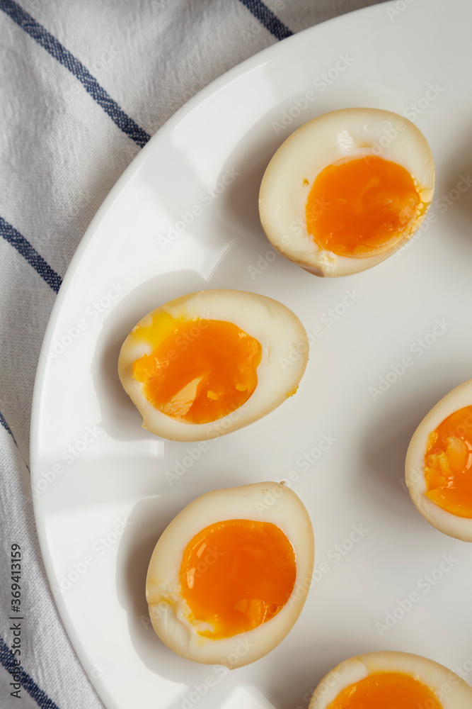 Homemade Unami Soy Sauce Eggs on a white plate, top view. Close-up. Homemade Unami Soy Sauce Eggs on a white plate, top view. Close-up.