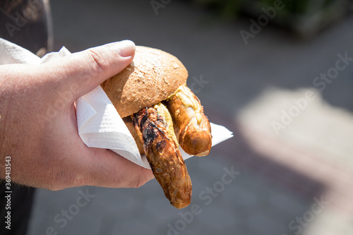 Mann isst ein Paar Bayreuther Bratwurst vom Grill im Weizen Brötchen vom Imbiss photo