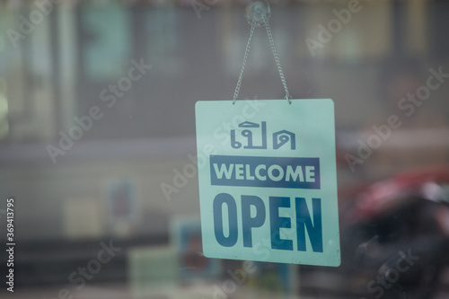 Open and welcome sign broad through the glass of window