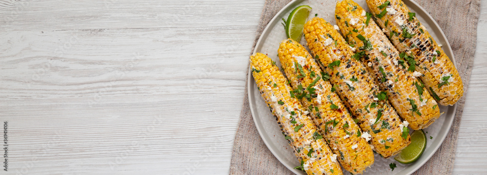 Φωτογραφία Homemade Elote Mexican Street Corn on a plate on a white wooden background, top view
