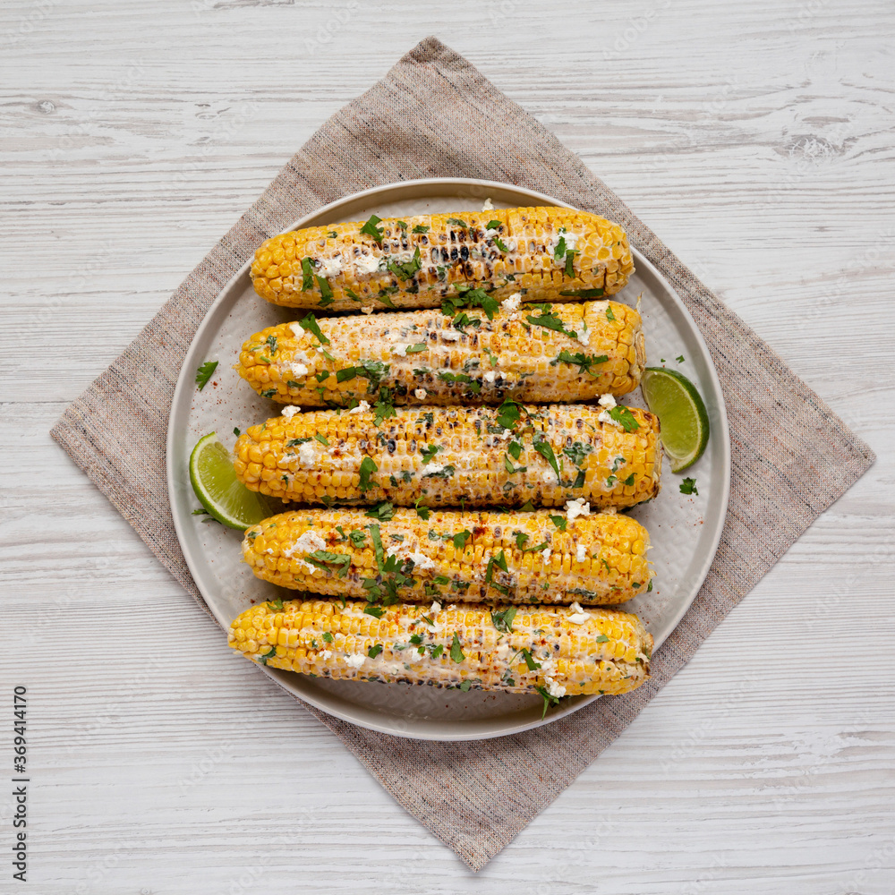 Φωτογραφία Homemade Elote Mexican Street Corn on a plate on a white wooden background, top view