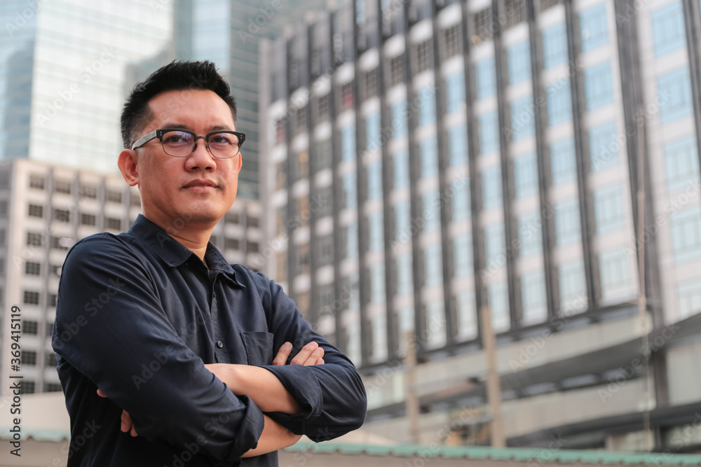 Confident male business executive with arms crossed standing in front of office building Confident male business executive with arms crossed standing in front of office building