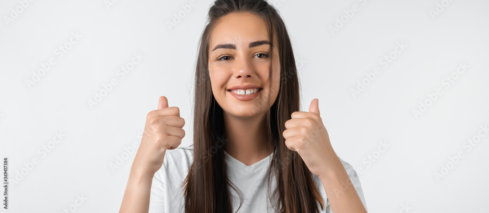 Good job. Pretty carefree modern stylish European girl with long chestnut hair making OK with both hands, gesture as if saying that everything is finee, white background.