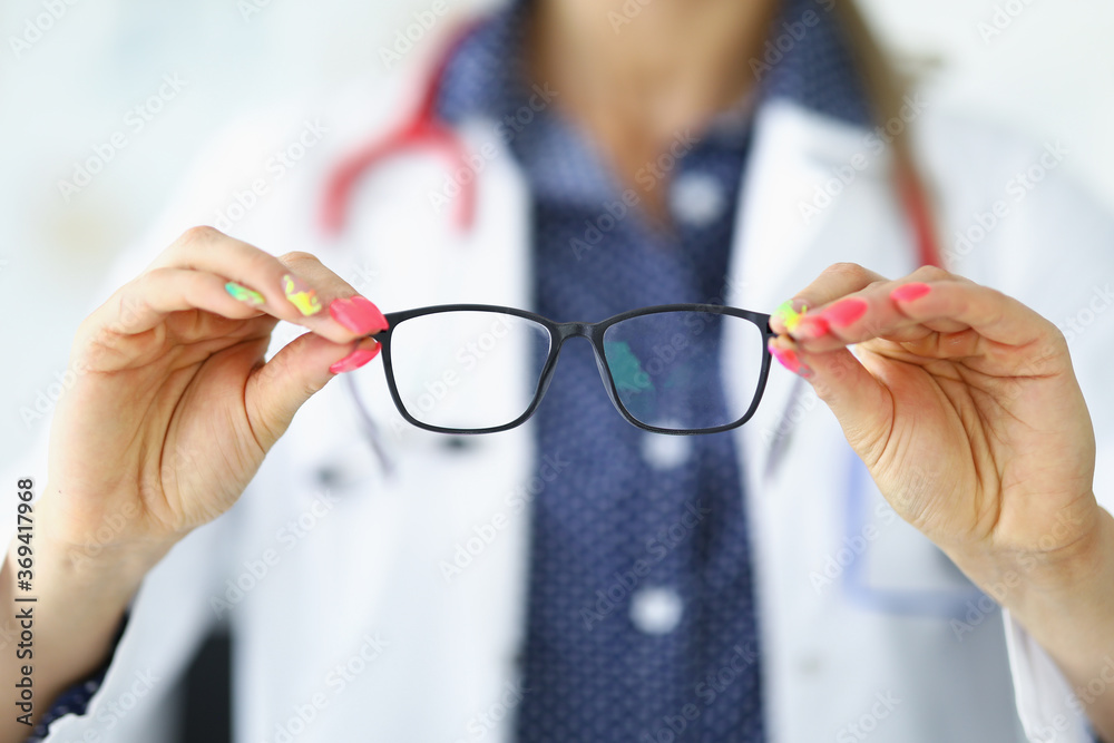 Woman in white medical coat holds glasses in her hands. Vision diagnostics by an optometrist concept