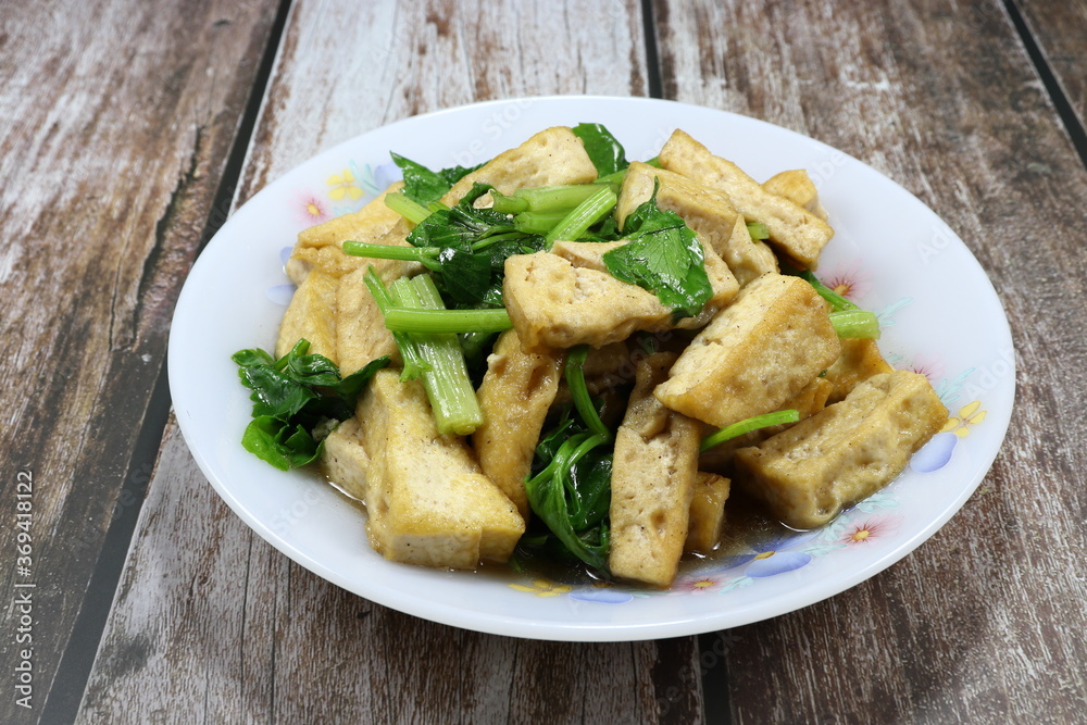 Traditional fried and stirred cutting tofu with Chinese celery and seasoning with soy sauce and pepper. Famous vegetarian food menu in Asia restaurant. Traditional fried and stirred cutting tofu with Chinese celery and seasoning with soy sauce and pepper. Famous vegetarian food menu in Asia restaurant.