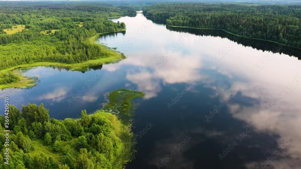 Aerial view of an elongated lake with winding coast and reflection of blue sky and clouds in water in the woods of Valday, Russia Aerial view of an elongated lake with winding coast and reflection of blue sky and clouds in water in the woods of Valday, Russia