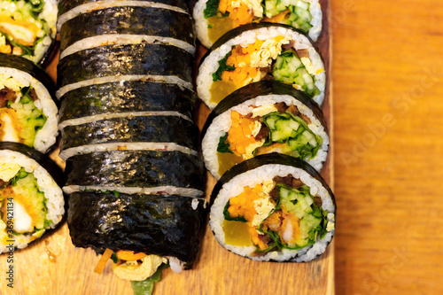 Korean kimpab rolls with vegetables and chicken on board, top view