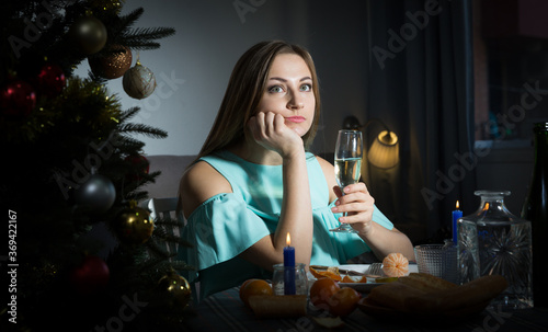Sad woman celebrating Christmas at home alone, sitting at festive table