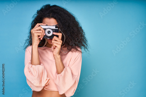 Portrait of a happy traveller girl with photo camera in her hand and looking in it. © Svitlana