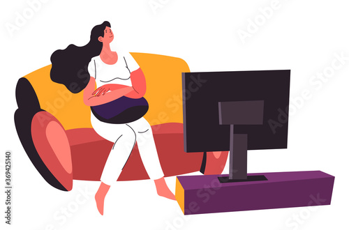 Woman watching television sitting on couch at home
