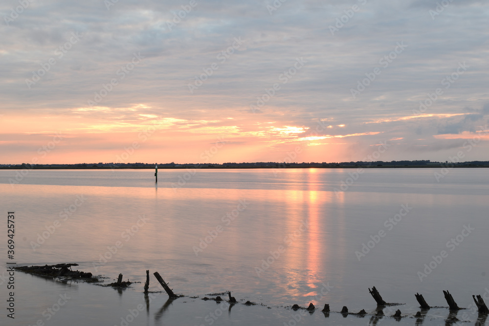 Naklejka premium Long exposure golden sunset over Breydon Water, a stretch of the River Yare at Great Yarmouth, Norfolk, UK
