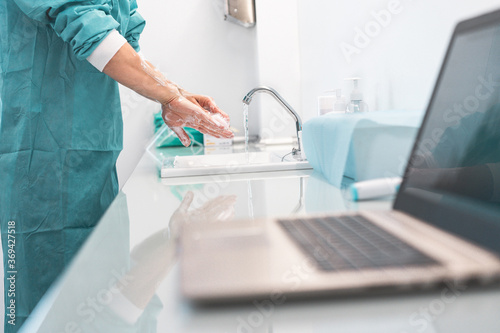 Surgeon doctor washing his hands before operating inside hospital during Coronavirus outbreak - Healthcare and hygiene concept - Focus on hands