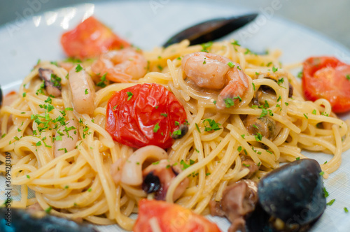 Spaghetti pasta with shrimp, mussels, tomatoes and cheese, close-up, side view. Tasty, traditional food Italians