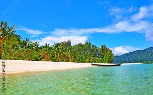 Beautiful uninhabited island without people with a tied Thai boat lying on the beach by the sea on a bright sunny day © Don Serhio