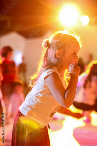 Blurred beautiful emotional young girl dancing in neon light. Human emotions, facial expression concept. Trendy colors.
