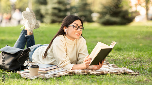 Girl reading a novel lying on the grass