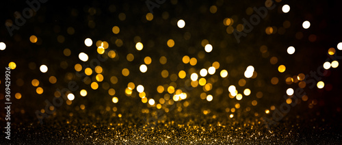 Abstract blurred background, yellow lights on black background. Golden christmas or new year bokeh. Defocused party night lights. © Sergey Peterman