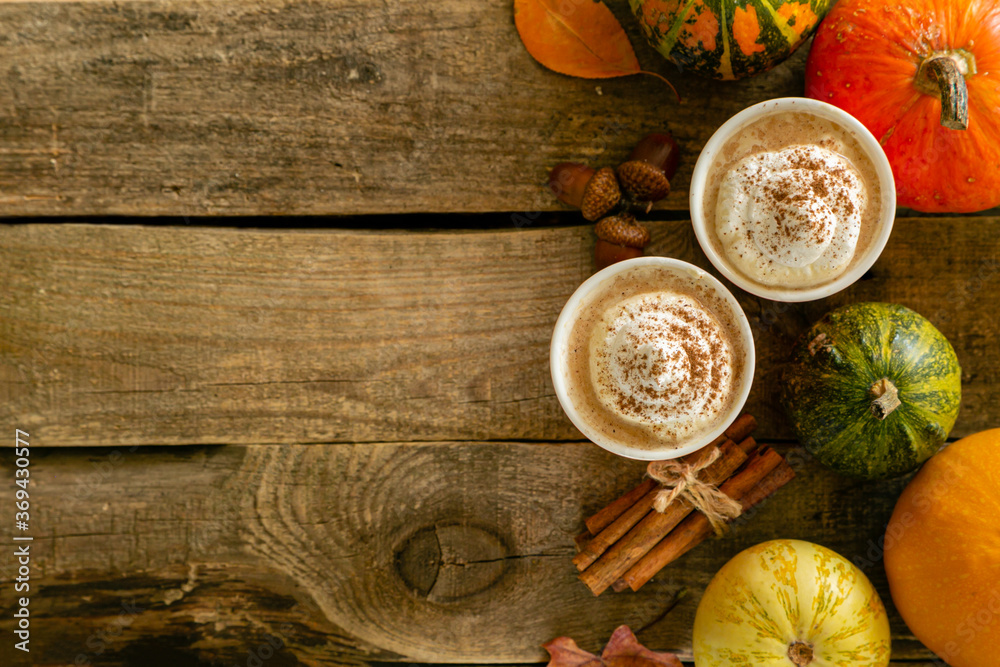 Fototapeta premium Pumpkin spiced latte in orange glasses on wood background, copy space
