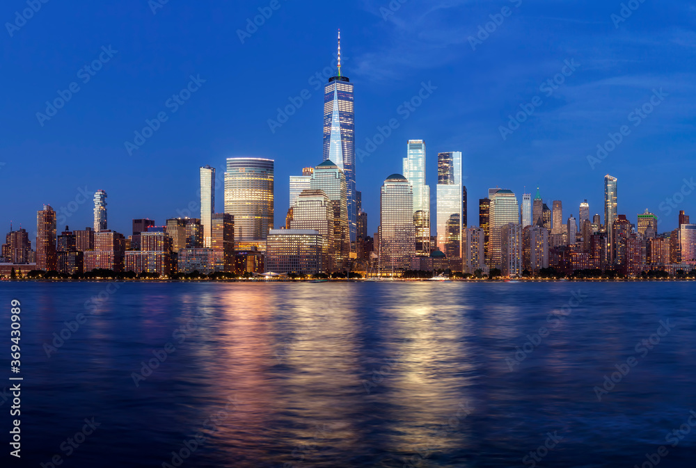 Obraz premium Manhattan skyline at dusk with city lights reflected in water, New York City, USA.