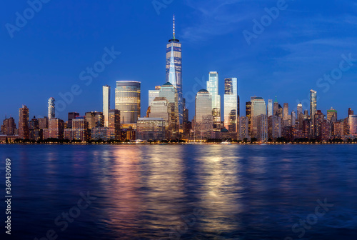 Manhattan skyline at dusk with city lights reflected in water, New York City, USA.