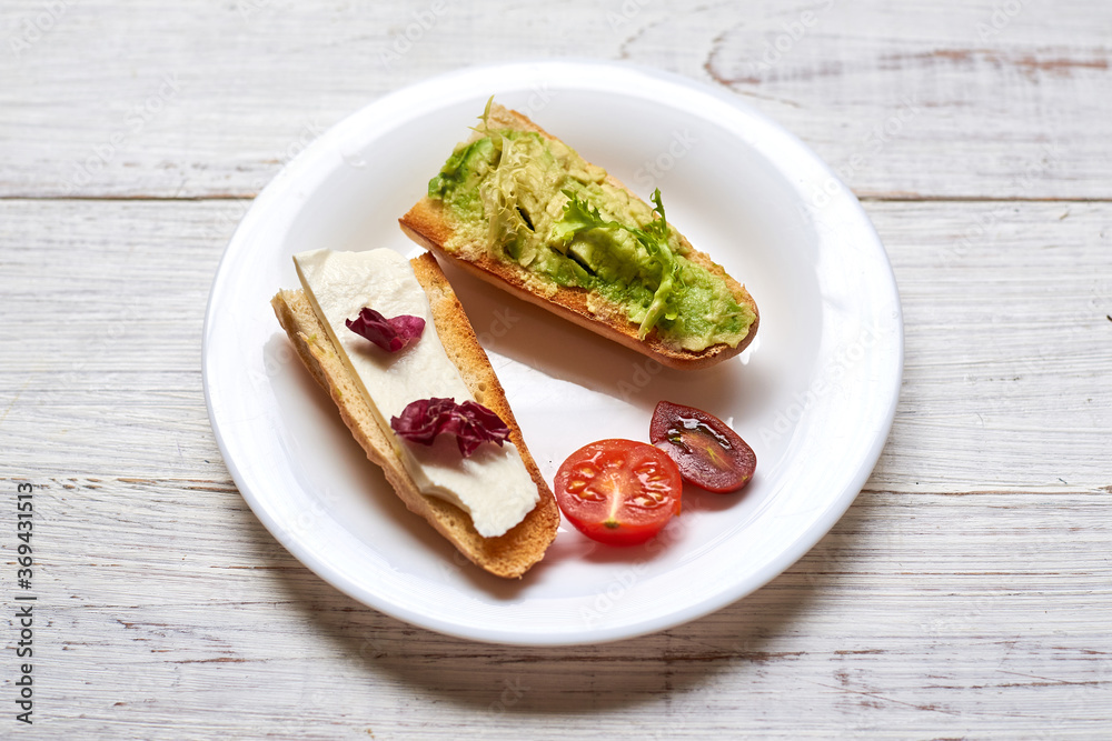 Toasted baguette with avocado and cheese. on a light wooden background.