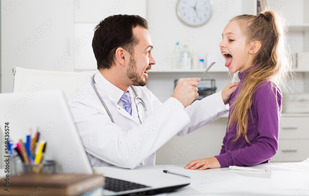 Fototapeta premium Little smiling girl visiting consultation with man doctor in hospital
