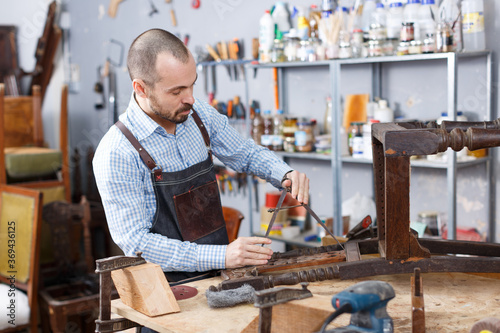 Craftsman engaged in retro chair repair in modern workshop