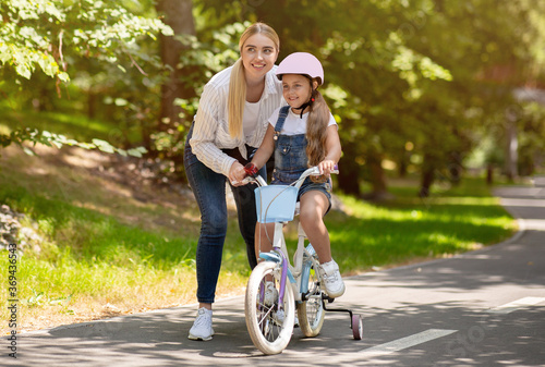 Mom Teaching Daughter To Ride Bicycle Spending Day In Park