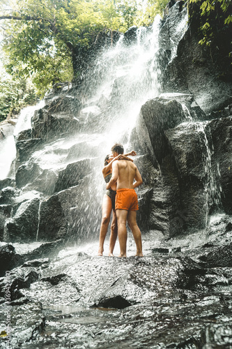 Young couple kissing under the waterfall