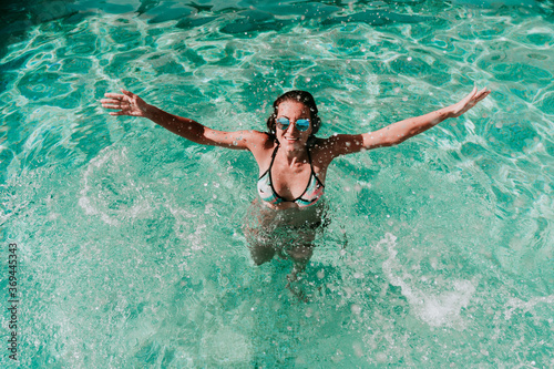 happy woman at the pool having fun splashing water. Summer and lifestyle