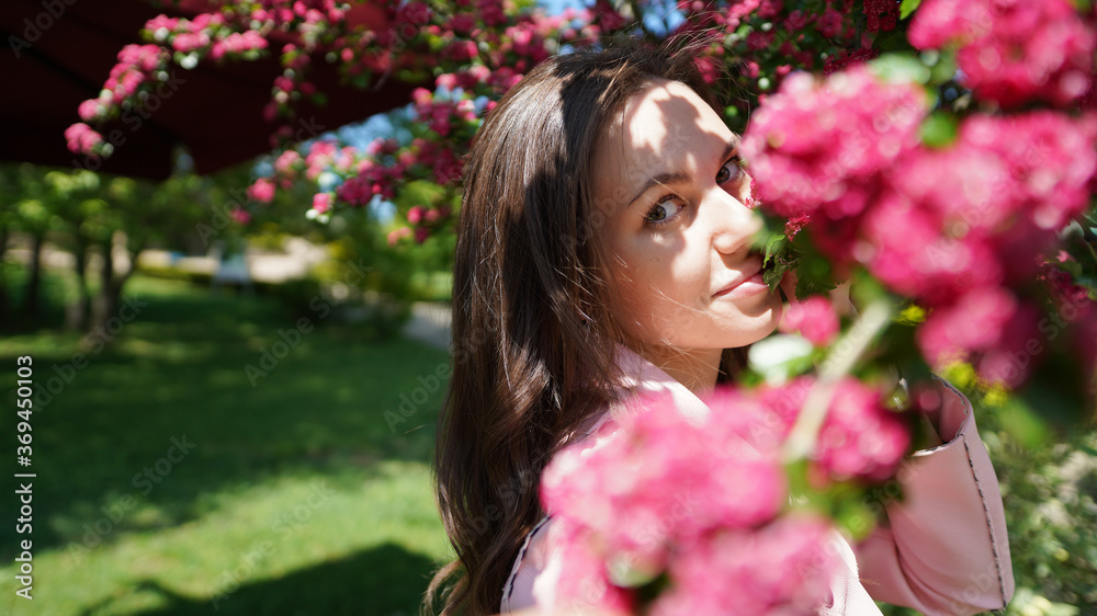 Portrait of pretty girl among branches of blossoming tree in spring in park Portrait of pretty girl among branches of blossoming tree in spring in park