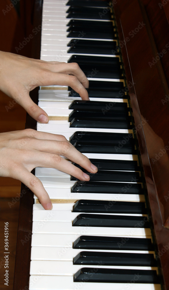 Hands playing the white and black keys of the piano.