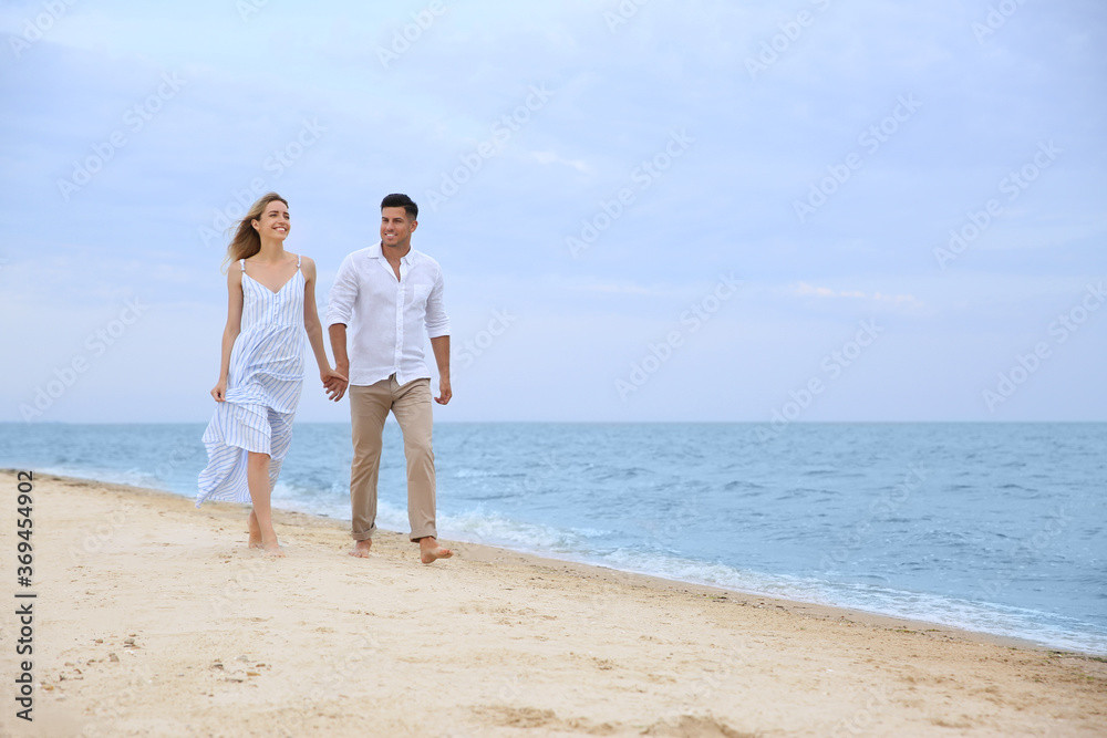 Happy couple having romantic walk on beach. Space for text Happy couple having romantic walk on beach. Space for text