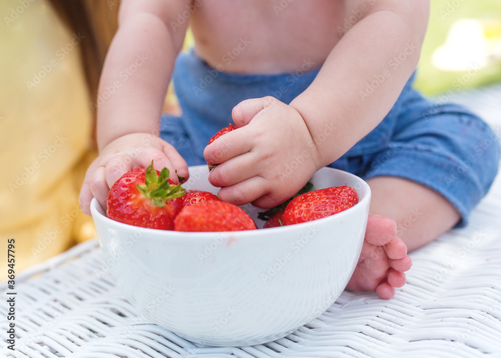 a child grabbing strawberries from a bowl a child grabbing strawberries from a bowl