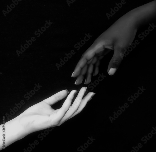 Monochromatic photo for two black & white hands with different positions showing unity, harmony, integration, and acceptance fighting against racism,prejudice, discrimination, racialism and xenophobia