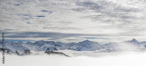 Snow covered mountains with inversion valley fog and trees shrouded in mist. Panoramic snowy winter landscape in Alps, Allgau, Kleinwalsertal, Bavaria, Germany.
