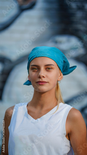 Young pretty girl in white shirt and blue head scarf on graffiti background