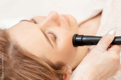 Young woman receiving RF lifting electric facial massage for face skin