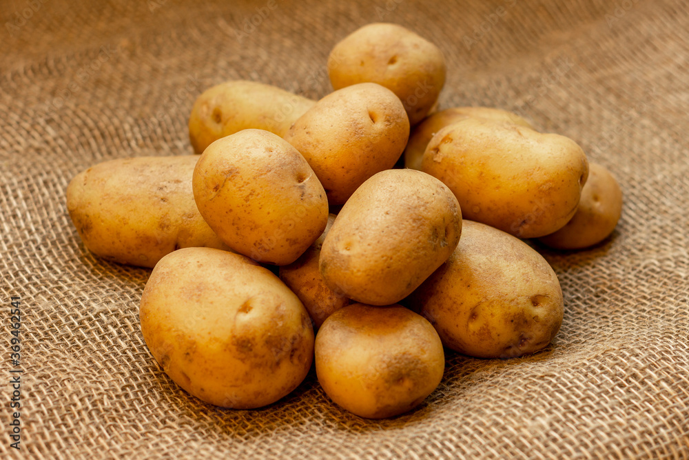 Tubers of young potatoes of a new crop lying on a table covered with burlap. Tubers of young potatoes of a new crop lying on a table covered with burlap.