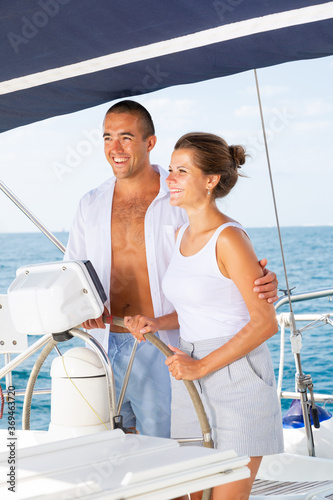 Loving couple steering yacht in calm blue ocean during romantic summer vacation © JackF
