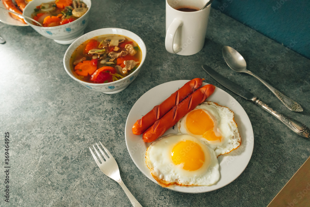 Breakfast set of fried egg sausages and vegetable soup served on the table. Breakfast set of fried egg sausages and vegetable soup served on the table.