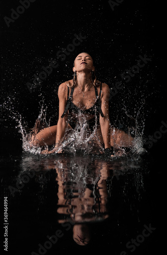 sexy girl splashes in the water. background is black