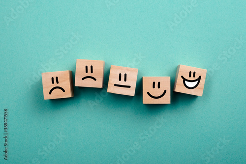 Wooden cubes with rating emotion faces from dissatisfied to happy